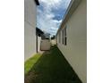 A narrow side yard featuring green grass, a white fence for privacy, and access to the backyard at 1556 N River Cir, Tarpon Springs, FL 34689