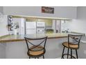 Charming kitchen bar with seating and a view into the kitchen, white appliances, and a paradise sign at 3710 41St S Way # D, St Petersburg, FL 33711