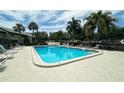 Community pool with lounge chairs and palm trees on a sunny day at 4215 E Bay Dr # 1702F, Clearwater, FL 33764