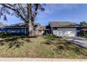 Inviting single-story home with well-maintained lawn, mature trees, red front door, and attached garage at 4617 Cloverlawn Dr, Tampa, FL 33624