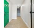 Bright hallway with a green door, leading to the staircase with wood-look tile flooring and fresh, white walls at 520 Wheaton Trent Pl, Tampa, FL 33619