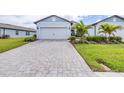 Paver driveway leading to a two-car garage of a single-Gathering home with manicured landscaping at 8435 Ocean Tides Cv, Parrish, FL 34219