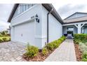 Exterior side view of home featuring an attached two-car garage, lovely landscaping, and paver walkway at 8435 Ocean Tides Cv, Parrish, FL 34219