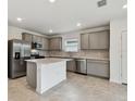 Bright kitchen boasts stainless steel appliances, gray cabinetry, and a functional center island at 10410 Cross River Trl, Parrish, FL 34219