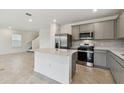Modern kitchen features stainless steel appliances, a center island, and elegant gray cabinets at 10410 Cross River Trl, Parrish, FL 34219