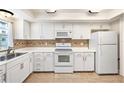 Bright kitchen featuring white cabinets, appliances, and decorative tile backsplash at 139 Bluff View Dr # 105, Belleair Bluffs, FL 33770