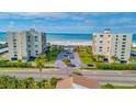 Aerial view of beachfront condos with manicured lawns and palm trees leading to the ocean at 1400 Gulf Blvd # 204, Clearwater Beach, FL 33767