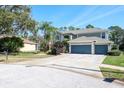 Inviting exterior showcases a three-car garage, mature trees, and manicured lawn at 4037 Auston Way, Palm Harbor, FL 34685