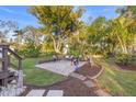 Lush backyard featuring a stone patio area with outdoor seating, surrounded by mature trees and landscaping at 5 N Jupiter Ave, Clearwater, FL 33755