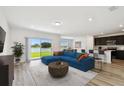 Bright living room featuring a lake view, a stylish blue couch, and an open layout to the modern kitchen at 10537 Hidden Banks Gln, Parrish, FL 34219