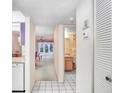 Hallway featuring white tile flooring, view of bathroom, dining, and living spaces at 1420 Oak Hill Dr # 102, Dunedin, FL 34698