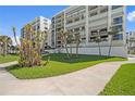 Lush lawn with palm trees, landscaping and walkway leading to the white beachfront condos at 1430 Gulf Blvd # 603, Clearwater Beach, FL 33767