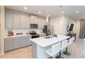 Modern kitchen with gray cabinets, stainless steel appliances, and a quartz countertop island at 2334 Audubon Preserve Ln, Lutz, FL 33558