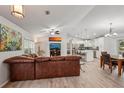 Open-concept living room featuring a leather sectional, modern art, and adjoined kitchen with island seating at 3655 Candia Ave, North Port, FL 34286