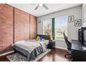 Bedroom with exposed brick accent wall and large windows overlooking the backyard at 4956 Rolling Green Dr, Wesley Chapel, FL 33543