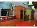 Bright kitchen with a stainless steel range hood, red countertops, and orange cabinetry at 7219 Williams S Dr, St Petersburg, FL 33705