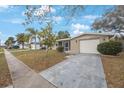Cozy single-story home featuring a curved screened porch and a paved driveway leading to a garage at 5317 Tammy Ln, Holiday, FL 34690
