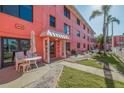 Exterior view of the apartment complex with a white awning entrance, chairs, and well-maintained landscaping at 6800 Sunset Way # 1003, St Pete Beach, FL 33706
