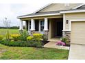 Welcoming home entrance with lush landscaping and a charming porch, perfect for enjoying the outdoors at 8438 Wheat Stone Dr, Zephyrhills, FL 33540