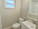 A bright, white bathroom with a standard toilet, vanity, and tile shower featuring a window for natural light at 9062 Sunrise Dr, Largo, FL 33773