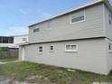 View of the back of the house showing gray siding, white trim, and a partially grassy backyard at 9062 Sunrise Dr, Largo, FL 33773