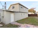 Exterior side and back of the house with light gray siding and a backyard showing a privacy fence at 9062 Sunrise Dr, Largo, FL 33773
