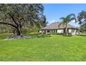 Expansive backyard features lush lawn, mature trees, and a stone patio with comfortable seating, ideal for outdoor living at 13532 Haflinger Way, Hudson, FL 34667