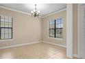 Bright, neutral living room with tile floors, large windows, and elegant chandelier at 15708 Oakleaf Run Dr, Lithia, FL 33547