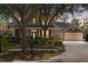 Charming home at dusk, showcasing stone details, a three-car garage, and mature trees at 15912 Ternglade Dr, Lithia, FL 33547