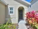 Close-up of the front entrance with an arched doorway and vibrant landscaping at 17014 Oval Rum Dr, Wimauma, FL 33598