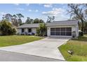 Well-manicured lawn leading to a light gray house with a black two car garage door and driveway at 20191 Rutherford Ave, Port Charlotte, FL 33952