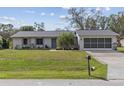 Inviting front exterior features a manicured lawn, mature palm, and a covered two-car garage at 20191 Rutherford Ave, Port Charlotte, FL 33952