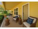 Inviting front porch with comfortable wicker seating and potted plants near the yellow front door at 2220 Spanish Dr # 4, Clearwater, FL 33763