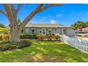 Beautifully landscaped front yard with a large tree shading a well-maintained gray brick house and white picket fence at 4135 Beach Se Dr, St Petersburg, FL 33705