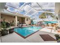 Inviting screened-in pool area complete with hot tub, a vibrant beach mural, and tropical accents at 5088 Championship Cup Ln, Spring Hill, FL 34609
