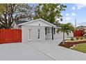 Charming single-story home featuring a gray exterior, a palm tree, a well-manicured lawn, and a red fence at 7480 Hobson Ne St, St Petersburg, FL 33702