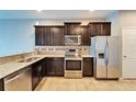 Modern kitchen featuring stainless steel appliances, granite countertops, and dark wood cabinets at 8842 Turnstone Haven Pl, Tampa, FL 33619