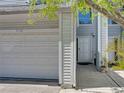 View of garage and front door with gray siding and white trim, complemented by a well-maintained landscape at 9718 Tiffany Oaks Ln # 12, Tampa, FL 33612