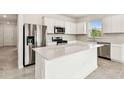 Modern kitchen featuring stainless steel appliances, white cabinets, and a large center island at 1226 Mumford Ct, Zephyrhills, FL 33540