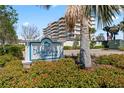 Community sign for Dolphin Harbour Condominiums with landscaping and a glimpse of the building in the background at 125 Island Way # 404, Clearwater Beach, FL 33767
