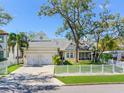 Inviting one-story home with a two-car garage, manicured lawn, and a charming white picket fence at 148 Chippewa Ave, Tampa, FL 33606