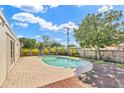 Backyard featuring a private pool surrounded by lush landscaping, a brick patio, and wood deck at 1510 Lakeside Dr, Dunedin, FL 34698