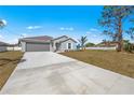 Gray home showcasing front yard, two-car garage, landscaping, and concrete driveway at 23343 Van Buren Ave, Port Charlotte, FL 33981