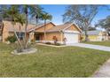 Well-maintained home featuring a lush green lawn, mature trees, and attached two-car garage at 4069 102Nd N Pl, Clearwater, FL 33762