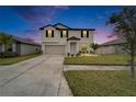 Charming two-story home at dusk featuring a well-manicured lawn and attached two-car garage at 8658 Parsons Hill Blvd, Wesley Chapel, FL 33545