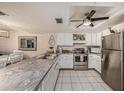 Well-lit kitchen boasts white cabinets, neutral countertops, stainless steel appliances, and tiled floor at 12924 Gulf Blvd # 110, St Petersburg, FL 33708