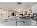 View of the kitchen's sink and cabinetry with open access to the bright living and dining area at 12924 Gulf Blvd # 110, St Petersburg, FL 33708