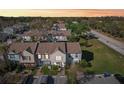Aerial view of townhouses with manicured lawns, parking spaces, and a serene neighborhood, under a vibrant sky at 16143 Rambling Vine E Dr, Tampa, FL 33624