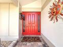 Close up view of the red front door adorned with a sun decoration and wreath at 1664 Ridge Top Way, Clearwater, FL 33765