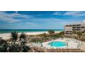 Outdoor pool with ocean views, lounge chairs, and lush tropical landscaping at 4450 Gulf Blvd # 303, St Pete Beach, FL 33706